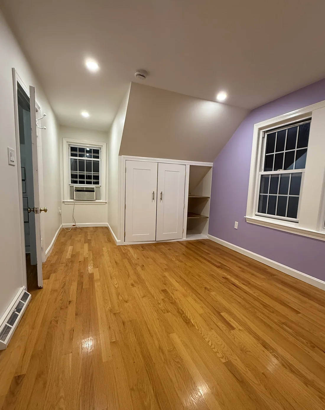 FG Professional Services project: attic bedroom after painting, with smooth white walls and ceiling, a lavender accent wall, and white trim