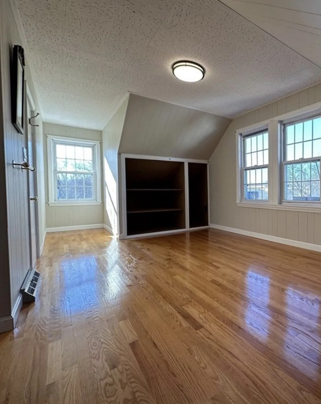 Before: attic bedroom before the project, with dated wall paneling and a heavily textured ceiling