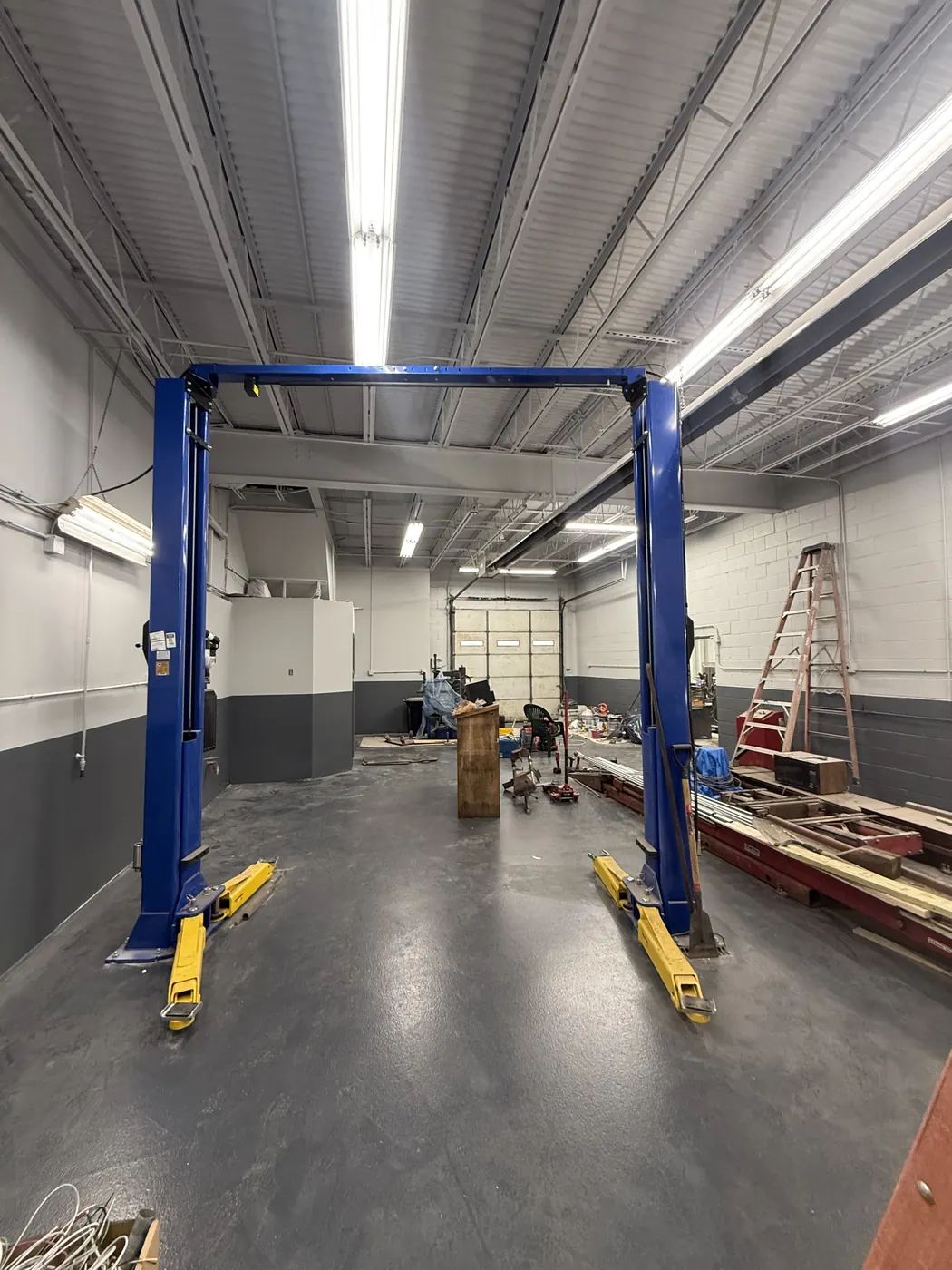 Auto shop with block walls painted white over charcoal and a blue car lift