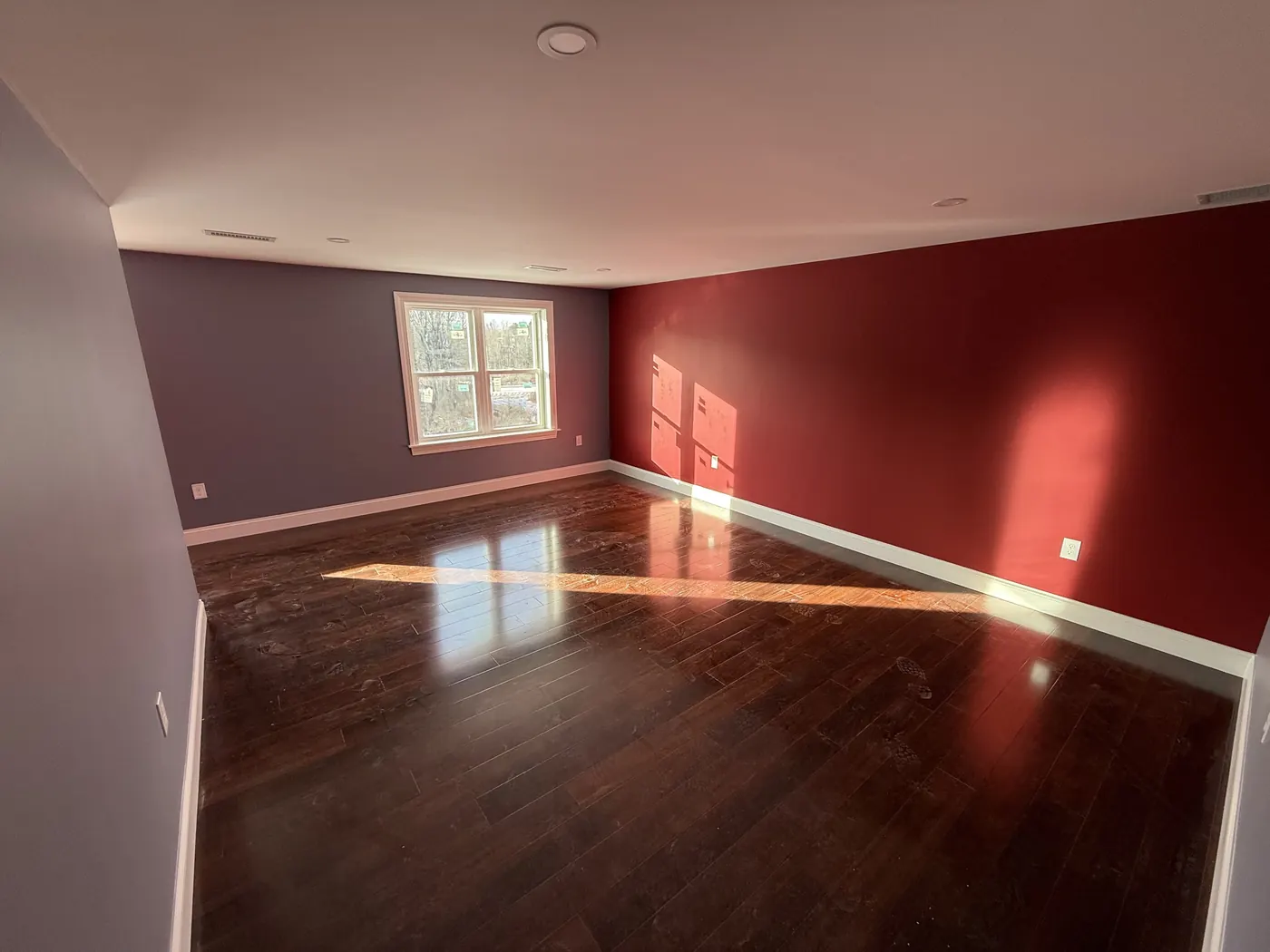 Large room with a deep red accent wall and warm gray walls