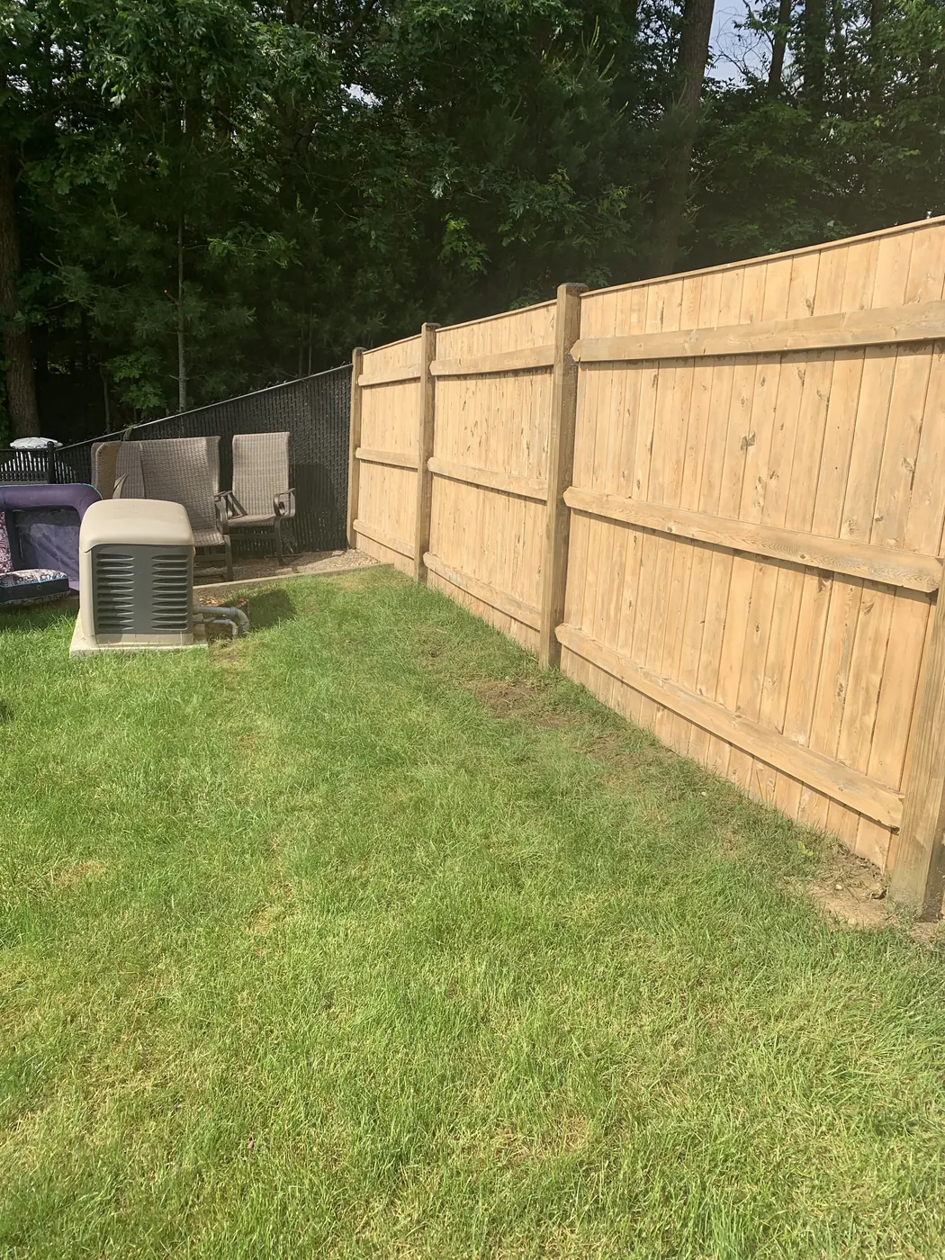 Stained wooden fence along a backyard lawn