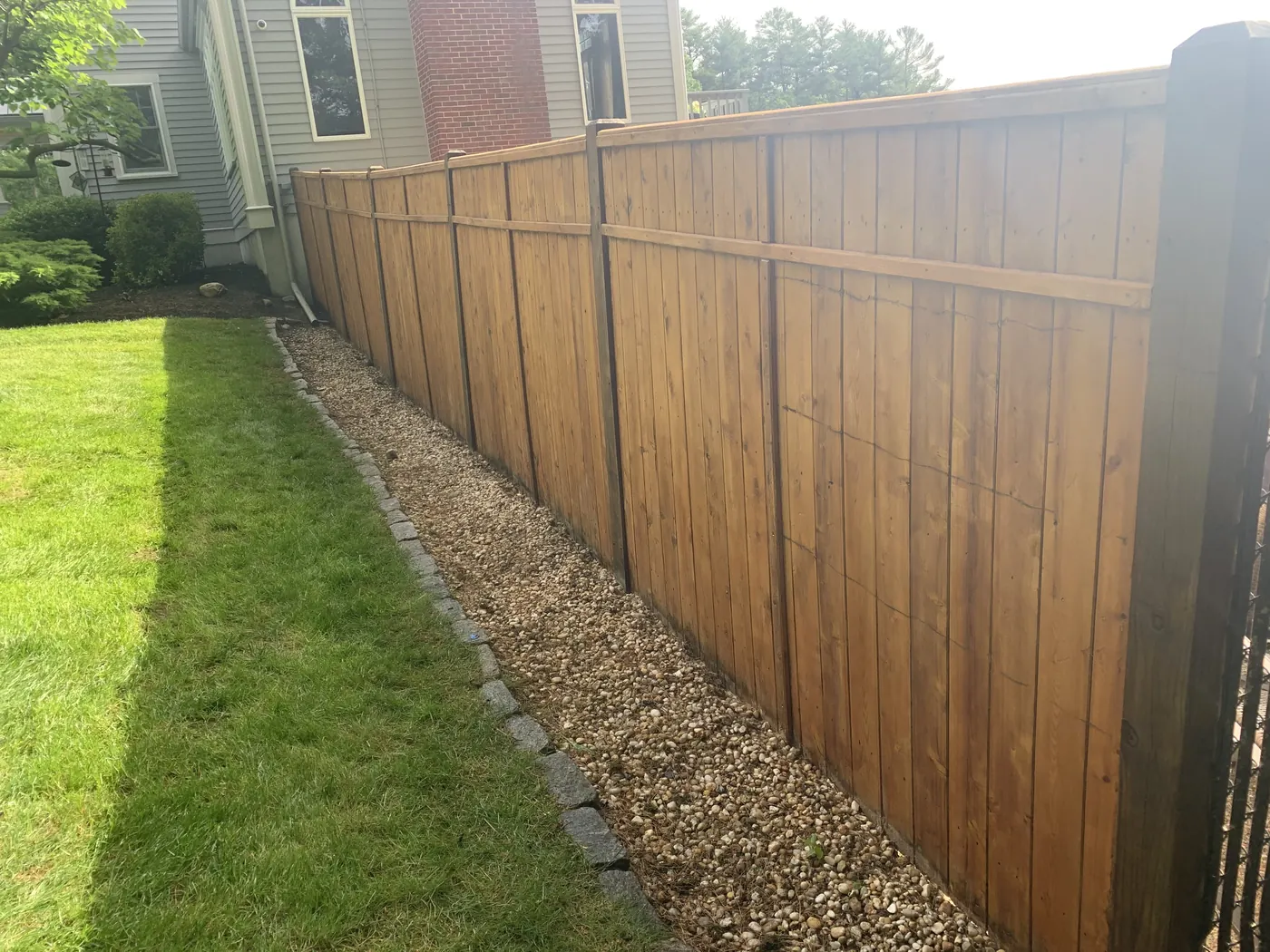 Long wooden privacy fence with a fresh warm stain